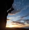 Athletic silhouette rock climbing. Sunrise sky with clouds. Copy space. Side view. Success, leading, chievements concept