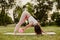 athletic, slender woman in pink clothes and small rubber ball doing Pilates on pink mat at dawn in park in summer