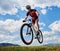 Athletic sportsman biker in professional sportswear flying in air on his bike on bright blue sky