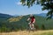 Athletic sportsman in sportswear cycling a bike in high grass under big green tree branch