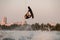 Athletic strong guy holds rope and energetically jumping and flip with wakeboard.