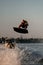 Athletic strong muscular man skillfully jumping on splashing wave on wakeboard