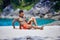 Athletic tattooed guy reading book on the sand at the beach