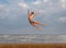 Athletic teenager on the beach in jump on the background of the sea and sky