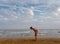 Athletic teenager on the beach in jump on the background of the sea and sky