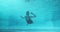 Athletic teenager girl swimmer underwater in blue outdoor pool, looking at camera