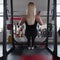 Athletic trainer of a young woman in black sportswear in gym sneakers. Girl doing exercises in a fitness studio. Back view.