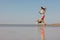 athletic woman and beagle dog run along sandy beach on seashore in morning. outdoor