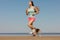 athletic woman and beagle dog run along sandy beach on seashore in morning. outdoor