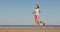 athletic woman and beagle dog run along sandy beach on seashore in morning. outdoor