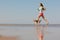 athletic woman and beagle dog run along sandy beach on seashore in morning. outdoor