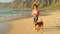 athletic woman with dog friend walks on the beach near the ocean plays with her