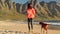 Athletic woman with dog friend walks on the beach near the ocean plays with her