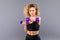 Athletic woman doing exercise for arms. Photo of muscular fitness model working out with dumbbells on grey background.