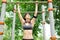 Athletic woman with earphones pulled on bar in park