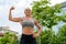 An athletic woman in a grey top flexing in the park