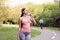 Athletic woman standing running track in summer park drink water after running exercises