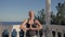 Athletic woman standing on the terrace with white columns overlooking the sea doing gymnastic exercises.