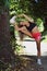 Athletic woman stretching against a tree