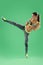 Athletic woman training her high kick in studio on green backgro