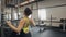 Athletic woman uses a lat pull-down machine sitting back to the camera