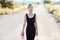 Athletic woman walking on rural road and carrying water bottle