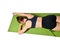 Athletic young girl lies face down on a yoga mat and stretches her arms forward in front of her.