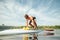 Athletic young man with sexy body gets up on sup board on water. Training on a rowing board on a sunny day