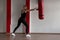 Athletic young woman blonde in a black T-shirt in black sports leggings in sneakers in red boxing gloves is standing