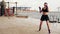 Athletic young woman shadow boxing by the sea. Beautiful female boxer training on the beach in the morning, throwing