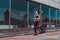 Athletics training, day morning. Young athletic woman running in summer on jogging in city, background glass windows of