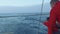 ATLANTIC - CIRCA NOVEMBER 2017: Close up view of yachtsman in red coat pulling fishing pole from water and other members