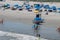 Atlantic City, New Jersey beach showing people on beach chairs sunbathing, many blue umbrellas and a lifeguard stand and boat