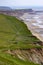 atlantic coast of Isle of wight in spring. A grassland meadow on top of coastal cliffs, a hiking path with backpackers,