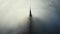 Atmospheric aerial shot, thick fog clouds flow covering famous majestic Mont Saint Michel fortress castle at sunrise.