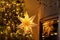 Atmospheric christmas eve. Stylish christmas illuminated star, decorated christmas tree with golden lights and festive decor on