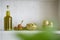 Atmospheric closeup shelf bottle olive oil bowl with green olives and oniens tomatoes in kitchen hous home,blurry green leaf in