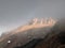 Atmospheric ghostly landscape with fuzzy silhouettes of sharp rocks in low clouds. Dramatic view to large mountains blurred in