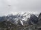 Atmospheric ghostly landscape with fuzzy silhouettes of snow rocks in low clouds. Dramatic view to large mountains blurred in rain