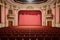 An atmospheric image capturing the timeless grace of an empty theater adorned with red seats and a majestic chandelier, Konferenz