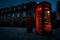 Atmospheric image of telephone box or phone booth in the street with historical architecture at night in London, England, UK