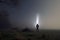 An atmospheric, moody concept. Of a man with a torch looking at the sky, in a field on a misty winters night. UK