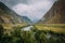 Atmospheric mountain landscape on a cloudy foggy day in the valley of Chulyshman. The river runs in a green valley