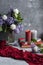 Atmospheric photo: bouquet of lilacs and carnations, a few large candles, books and jewelry on a gray background