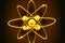 atomic particles rotating on bright yellow illuminated model atom orbit