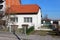 Attached small white suburban family house with renovated new roof next to unfinished large red building blocks house