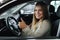 Attactive young bussines woman sitting in car in car showroom. Woman choosing new car. Beautiful blond hair female in