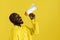Attention! Black man shouting in megaphone on yellow background