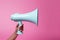 Attention grabber Hand with blue megaphone against pink backdrop, free