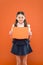 Attention please. school girl hold paper on orange background. copy space. happy little girl in school uniform with add